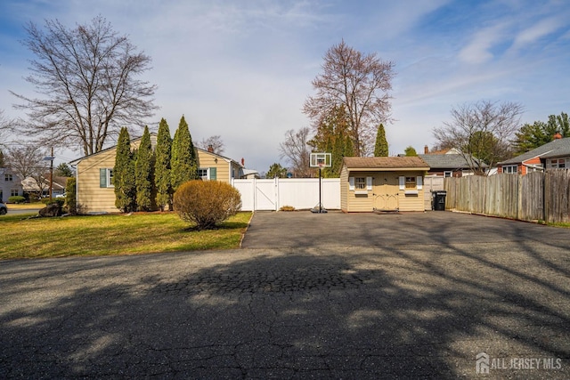 view of yard with fence, a gate, and aphalt driveway