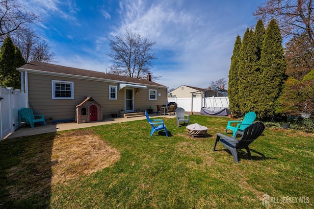 back of house featuring a yard, a patio, a fenced backyard, and an outdoor fire pit
