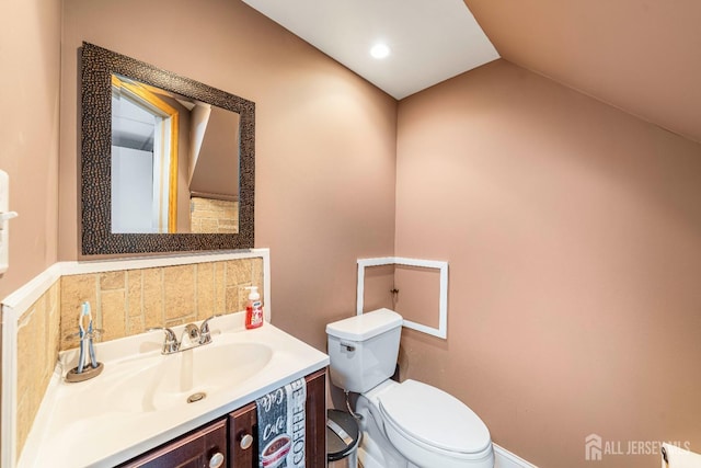 bathroom featuring tasteful backsplash, vanity, vaulted ceiling, and toilet