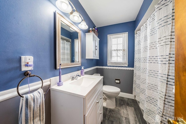bathroom with baseboards, curtained shower, toilet, vanity, and wood finished floors