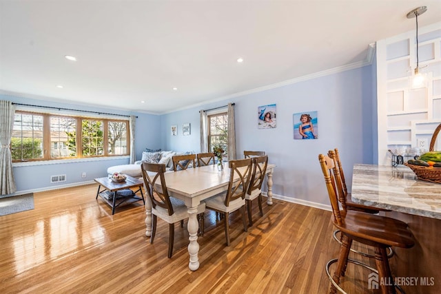 dining space with light wood finished floors, baseboards, and crown molding