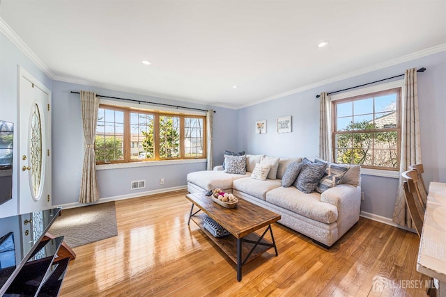 living room featuring visible vents, baseboards, crown molding, and light wood-style flooring