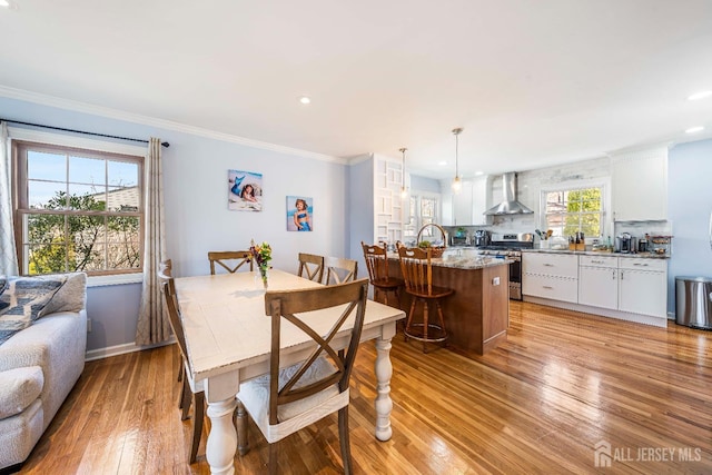 dining space with light wood finished floors, baseboards, ornamental molding, and recessed lighting