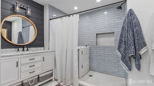 full bath with tile walls, vanity, a tile shower, and recessed lighting