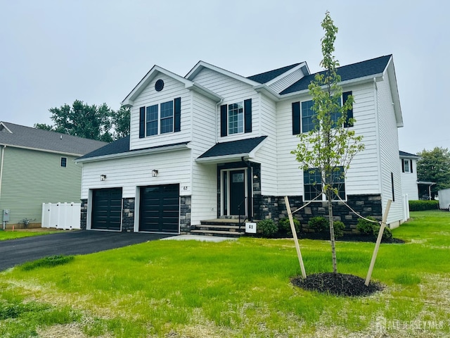 view of front of house with asphalt driveway, a garage, a front lawn, and stone siding