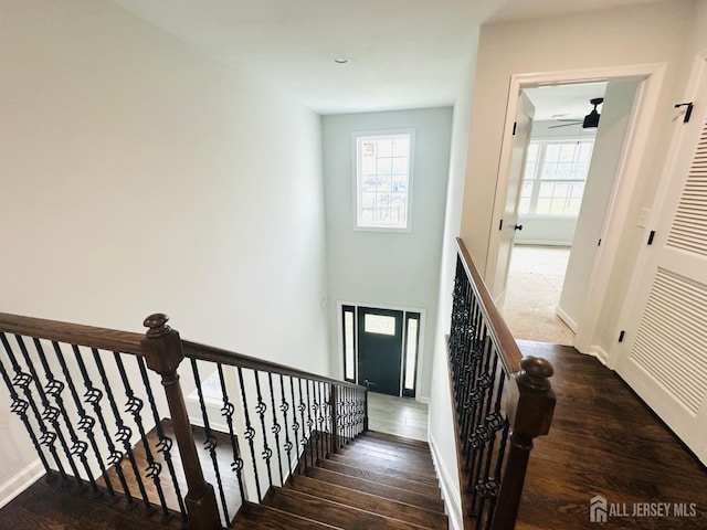 staircase featuring hardwood / wood-style flooring, a ceiling fan, and baseboards