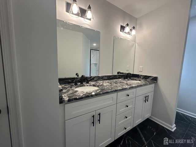 bathroom with marble look tile flooring, baseboards, double vanity, and a shower