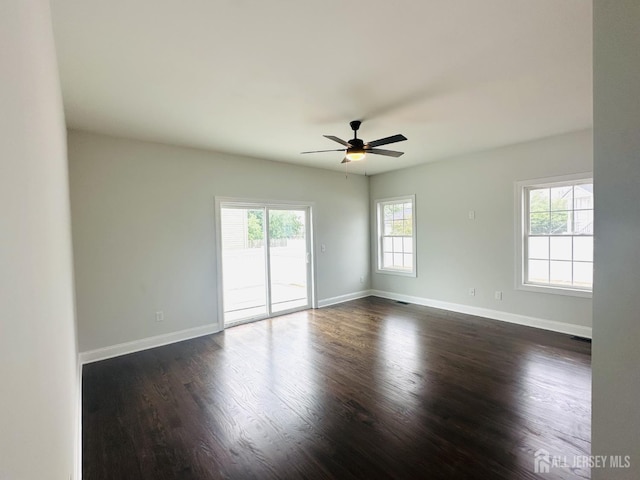 spare room featuring ceiling fan, dark wood-style floors, and baseboards
