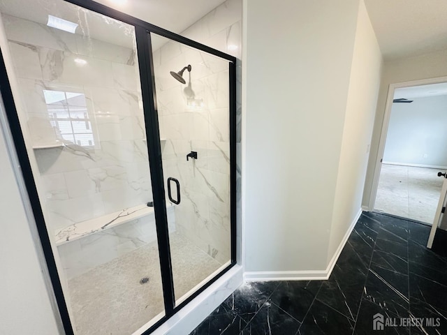 full bath featuring marble finish flooring, baseboards, and a marble finish shower