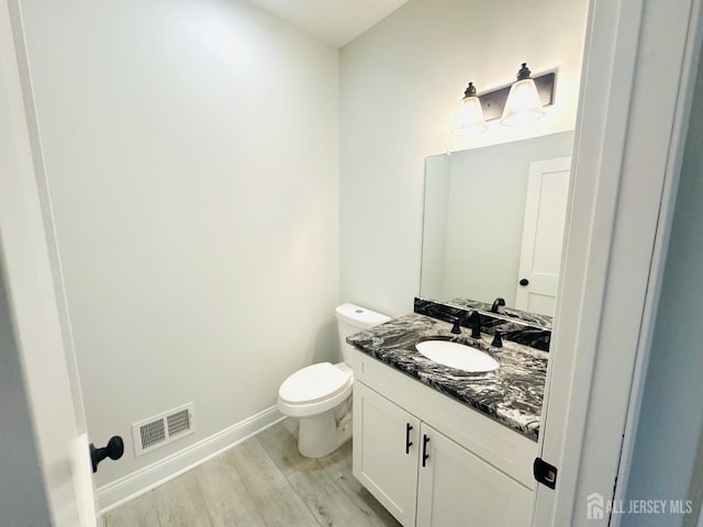 bathroom featuring wood finished floors, vanity, toilet, and baseboards