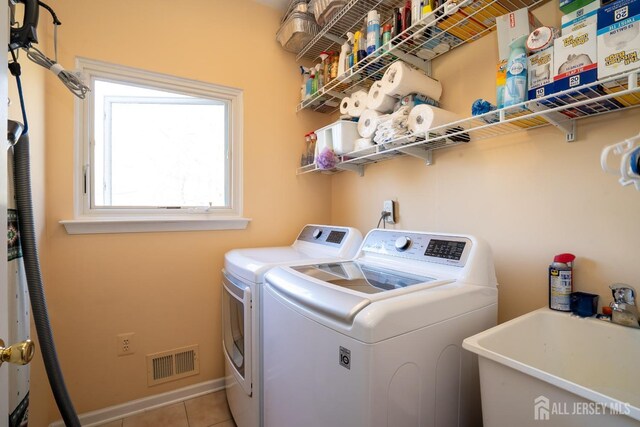 laundry area with separate washer and dryer, sink, and light tile patterned floors