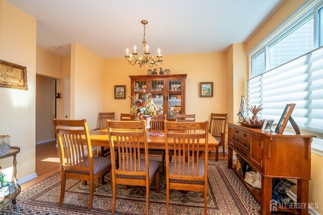 dining room featuring plenty of natural light, wood-type flooring, and a notable chandelier