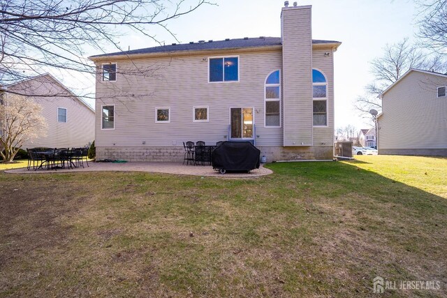 rear view of property with cooling unit, a patio area, and a lawn