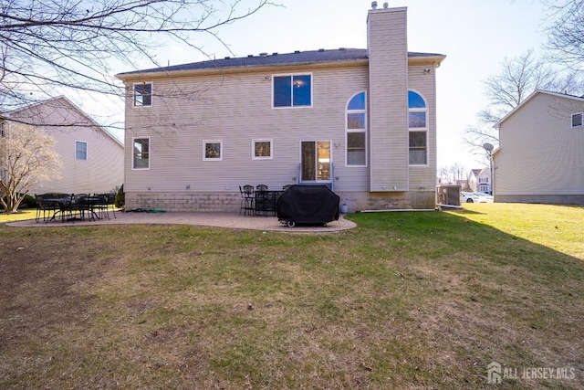 rear view of house featuring a patio, central air condition unit, a yard, and a chimney