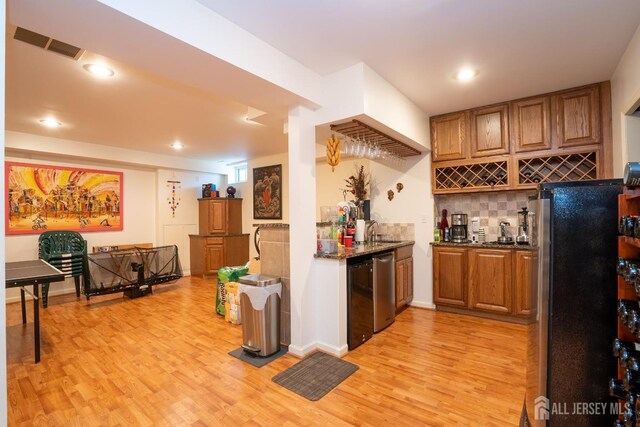 kitchen with backsplash, dark stone countertops, sink, and light wood-type flooring