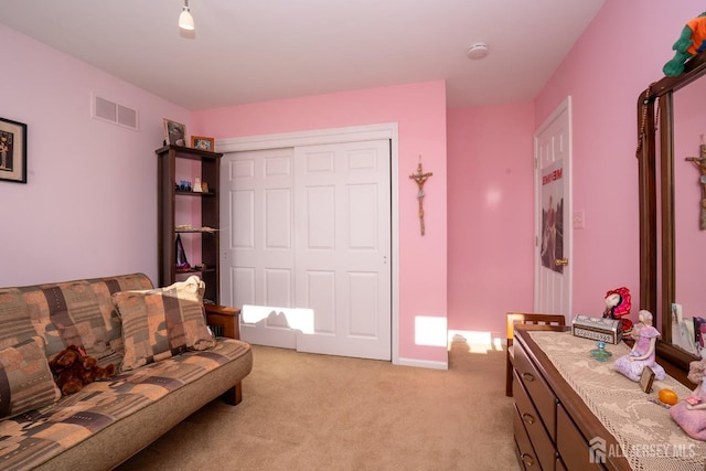 bedroom with visible vents, light colored carpet, and a closet