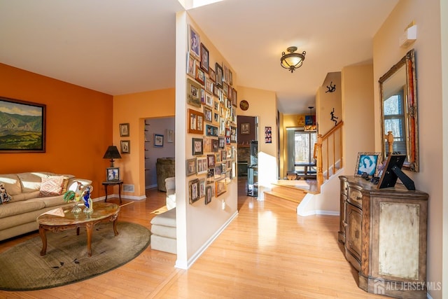 hall featuring stairway, visible vents, baseboards, and light wood finished floors