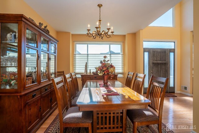 dining area with light hardwood / wood-style floors and a notable chandelier