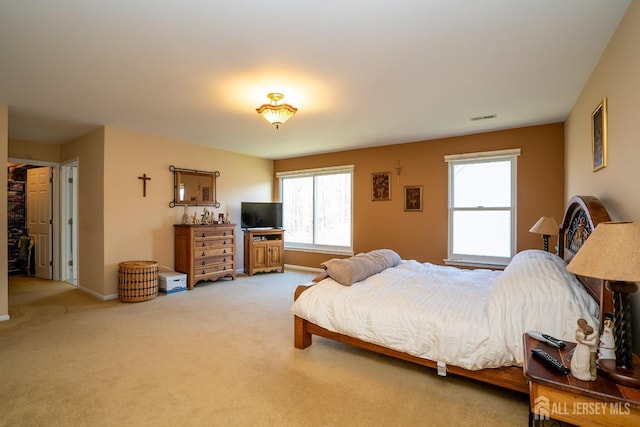 bedroom featuring visible vents, light colored carpet, and baseboards