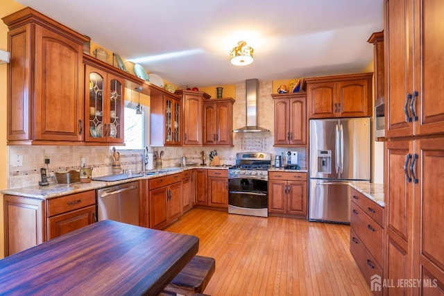 kitchen with sink, light hardwood / wood-style flooring, stainless steel appliances, light stone countertops, and wall chimney exhaust hood