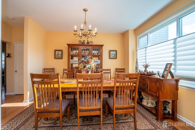 dining space featuring baseboards, an inviting chandelier, and wood finished floors