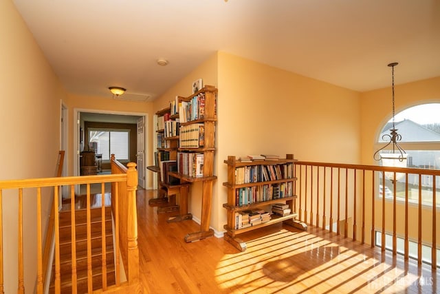 hall with an upstairs landing and wood finished floors