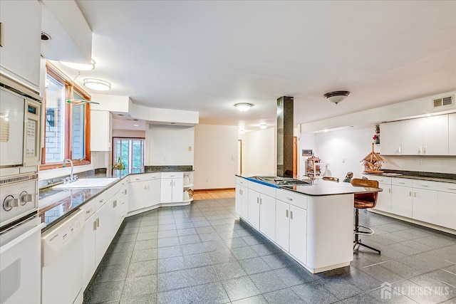 16 Benedek Rd, Princeton, NJ 08540 - kitchen featuring white appliances, a sink, a peninsula, dark countertops, and white cabinets