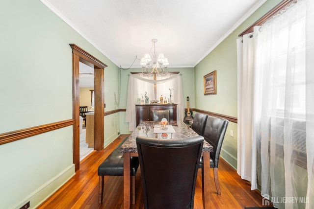 dining space featuring dark hardwood / wood-style flooring, a notable chandelier, and ornamental molding