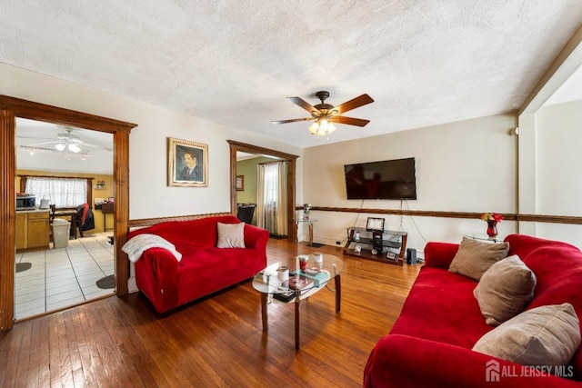 living room with hardwood / wood-style flooring, a textured ceiling, and ceiling fan