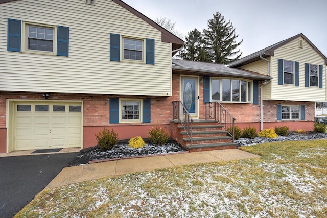 split level home with brick siding, an attached garage, and aphalt driveway