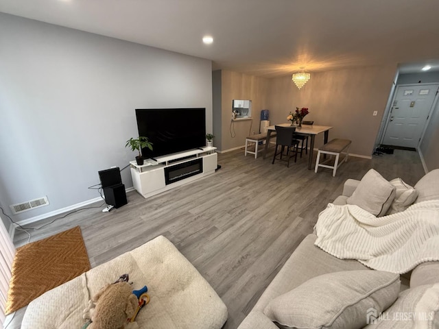 living area with baseboards, visible vents, and wood finished floors