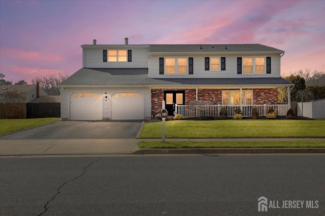 view of front of home featuring covered porch, a lawn, an attached garage, fence, and driveway