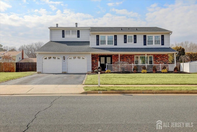 traditional-style house with a garage, covered porch, driveway, and a front lawn