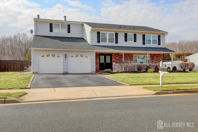 traditional home featuring a front yard, covered porch, driveway, and an attached garage