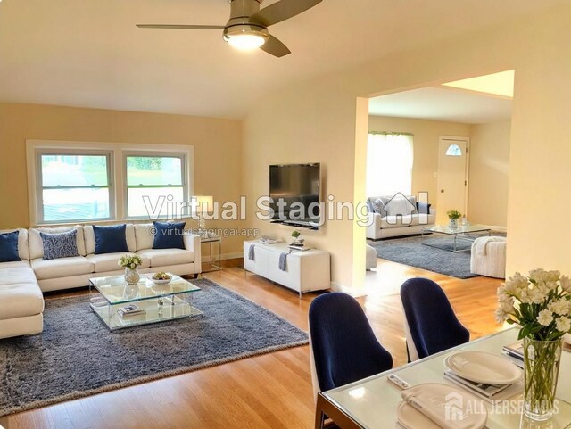 living room with a wealth of natural light, light hardwood / wood-style floors, vaulted ceiling, and ceiling fan