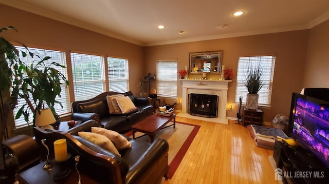 living area featuring baseboards, a fireplace with flush hearth, recessed lighting, light wood-style floors, and crown molding