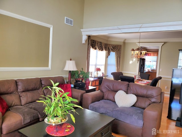 living room with a wealth of natural light, visible vents, a chandelier, and light wood-style floors