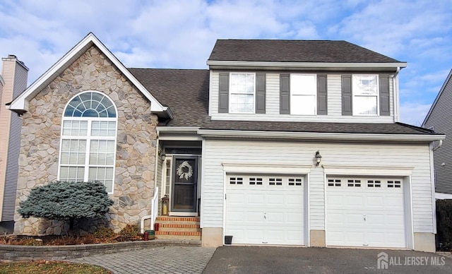 traditional-style house featuring aphalt driveway, an attached garage, and a shingled roof