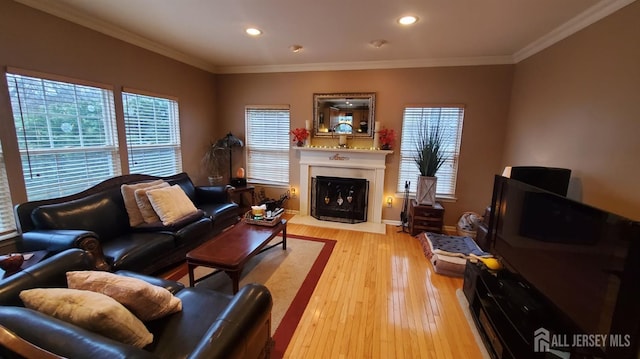 living room featuring recessed lighting, a fireplace, light wood-type flooring, and ornamental molding