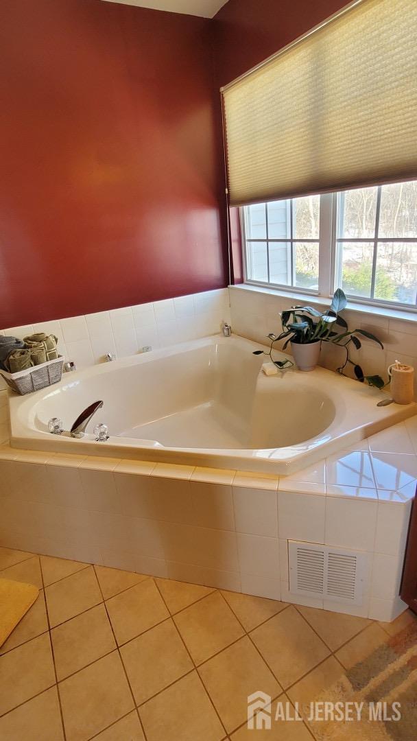 bathroom with tile patterned flooring, visible vents, and a garden tub