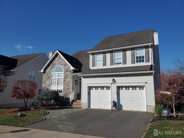 traditional home featuring a garage, stone siding, and driveway