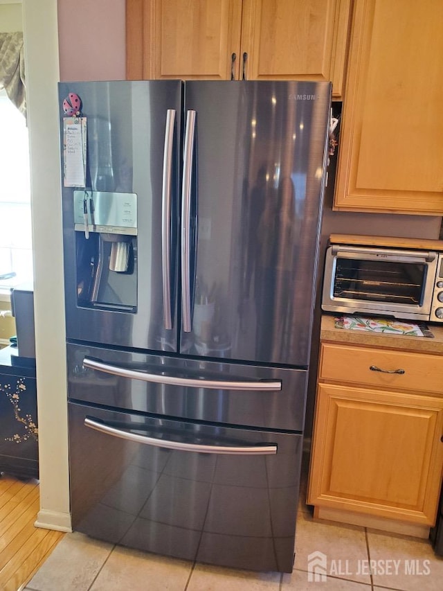 kitchen featuring light tile patterned flooring, a toaster, and stainless steel refrigerator with ice dispenser