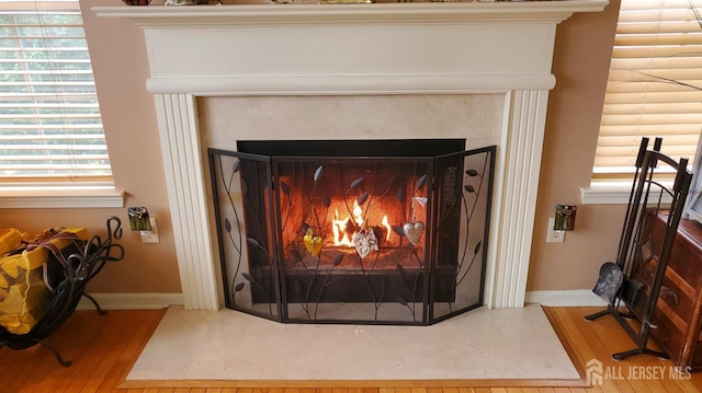 room details featuring a fireplace with flush hearth, baseboards, and wood finished floors