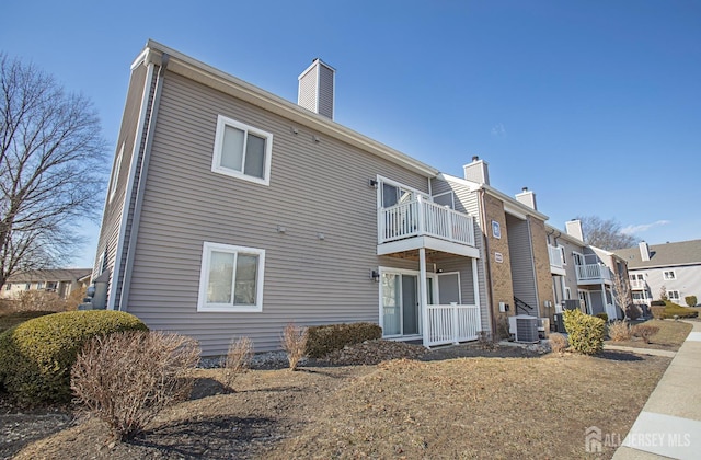 back of property with a residential view, cooling unit, a chimney, and a balcony