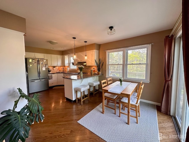 dining space with baseboards, plenty of natural light, and dark wood-type flooring