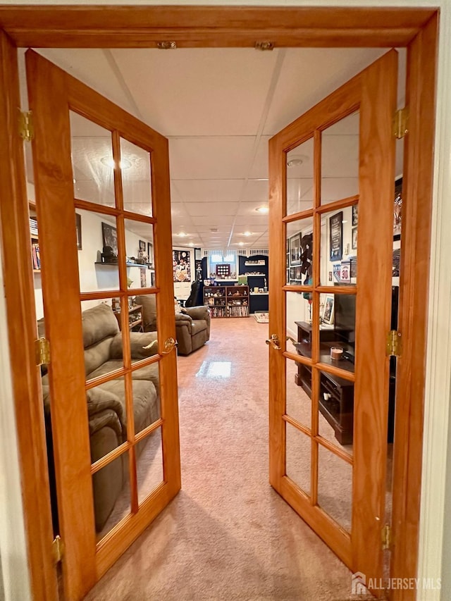 corridor with carpet floors, a paneled ceiling, and french doors