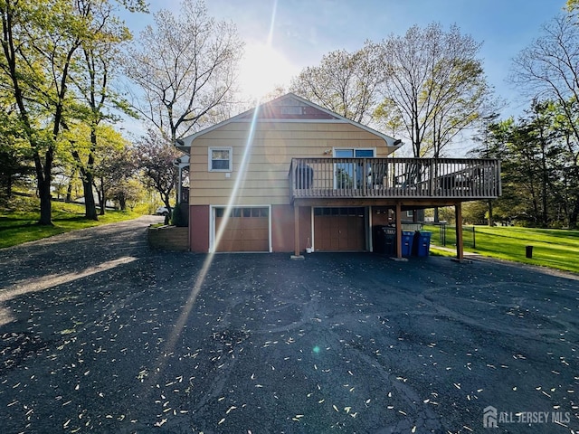 view of side of home with a deck, a garage, and aphalt driveway