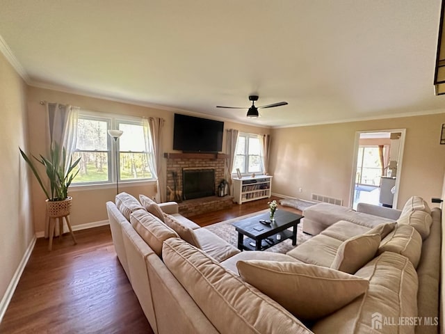 living room featuring visible vents, a fireplace, baseboards, dark wood-style floors, and ornamental molding