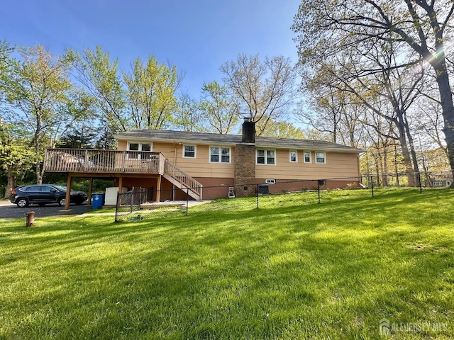 back of property with a lawn, a wooden deck, stairway, and fence