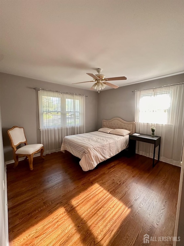 bedroom featuring a ceiling fan, multiple windows, and wood finished floors